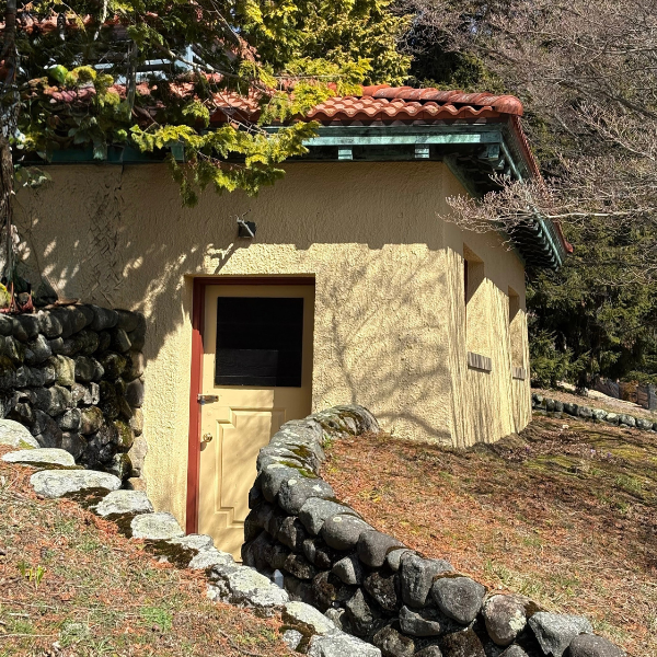 comfort station building in wilcox park yellow with rust colored scalloped roof and stone wall entrance