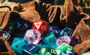 A bunch of various polyhedral dice in a brown cloth bag.