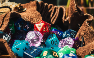 A bunch of various polyhedral dice in a brown cloth bag.